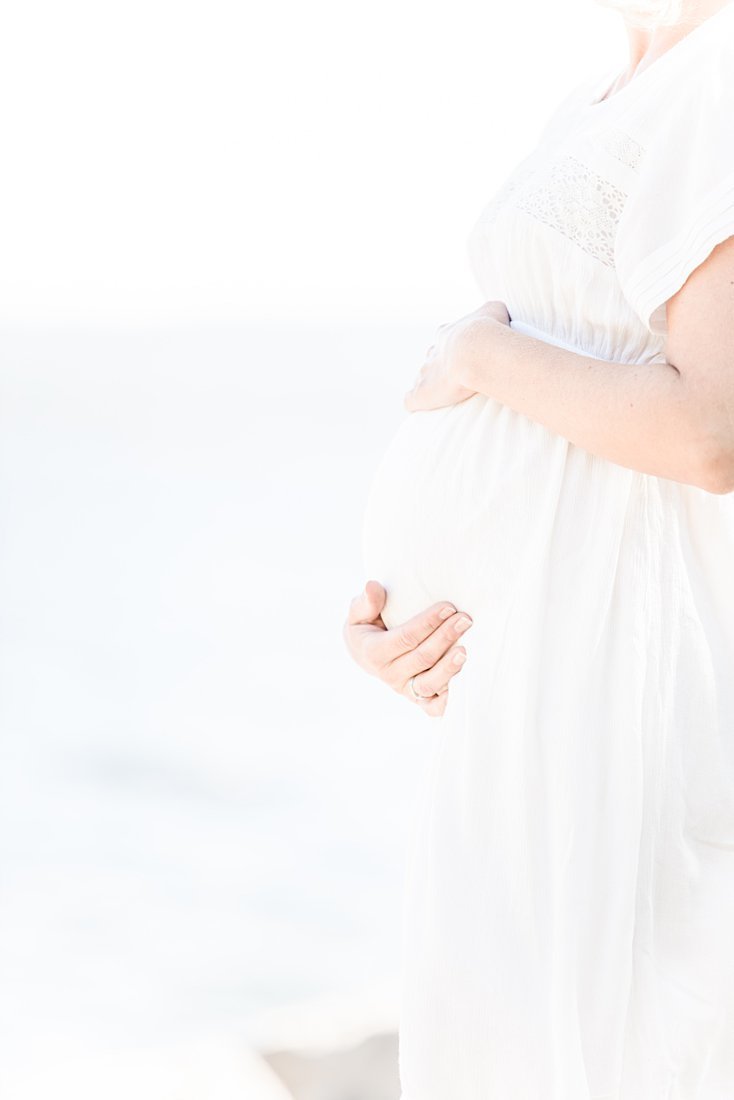 En gravid kvinne som holder rundt magen sin under gravidfotografering
