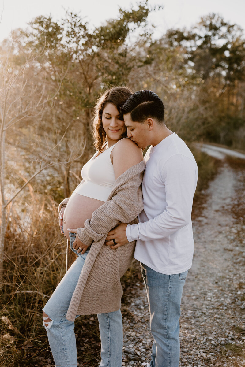 Husband embracing his pregnant wife at sunset.