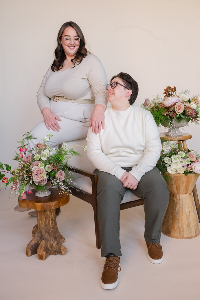 Two people standing next to someone sitting in a chair as they all smile