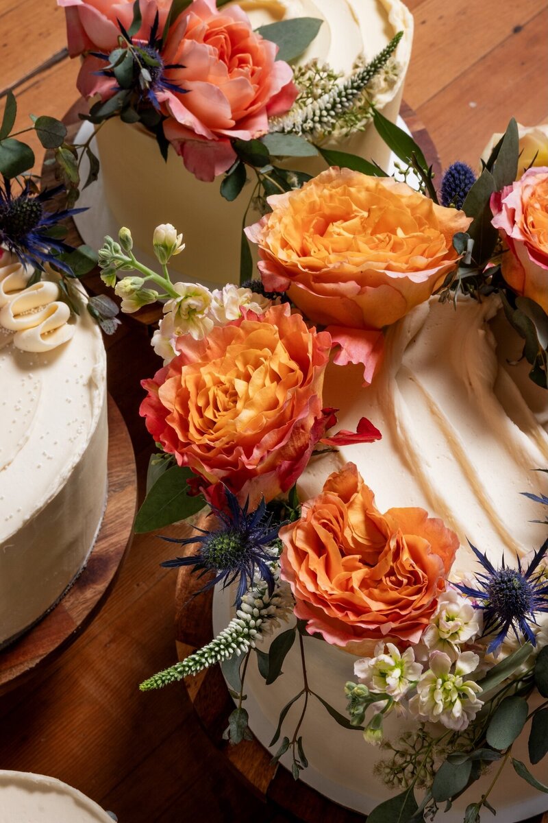 Decorated gluten-free wedding cake adorned with vibrant orange and purple flowers, handcrafted by Grain Artisan Bakery in Snohomish, Washington.