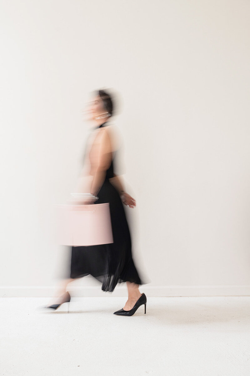 A blurred artistic portrait of a woman in motion carrying a pink case, symbolizing the presence, movement, and emotional depth at the heart of Kari Dawson + Co's candid wedding photography