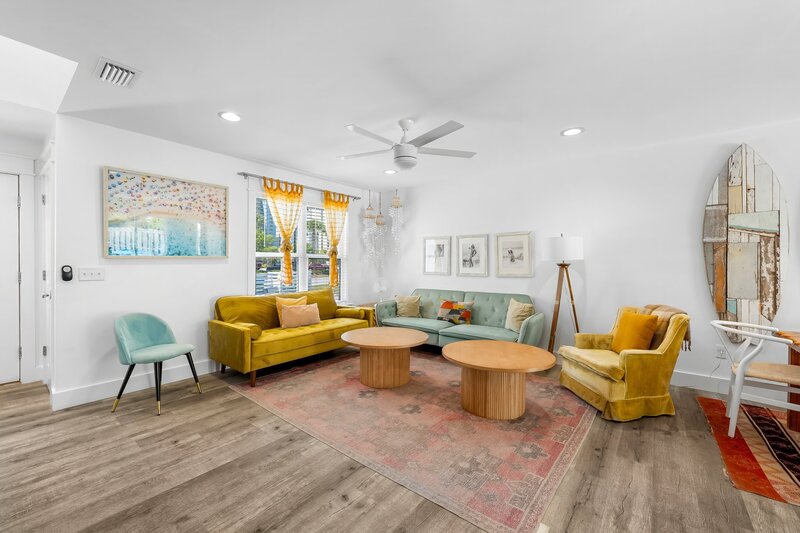 Vibrant living room at the Surf House featuring mid-century modern furniture, coastal artwork, and a cozy, beachy vibe.