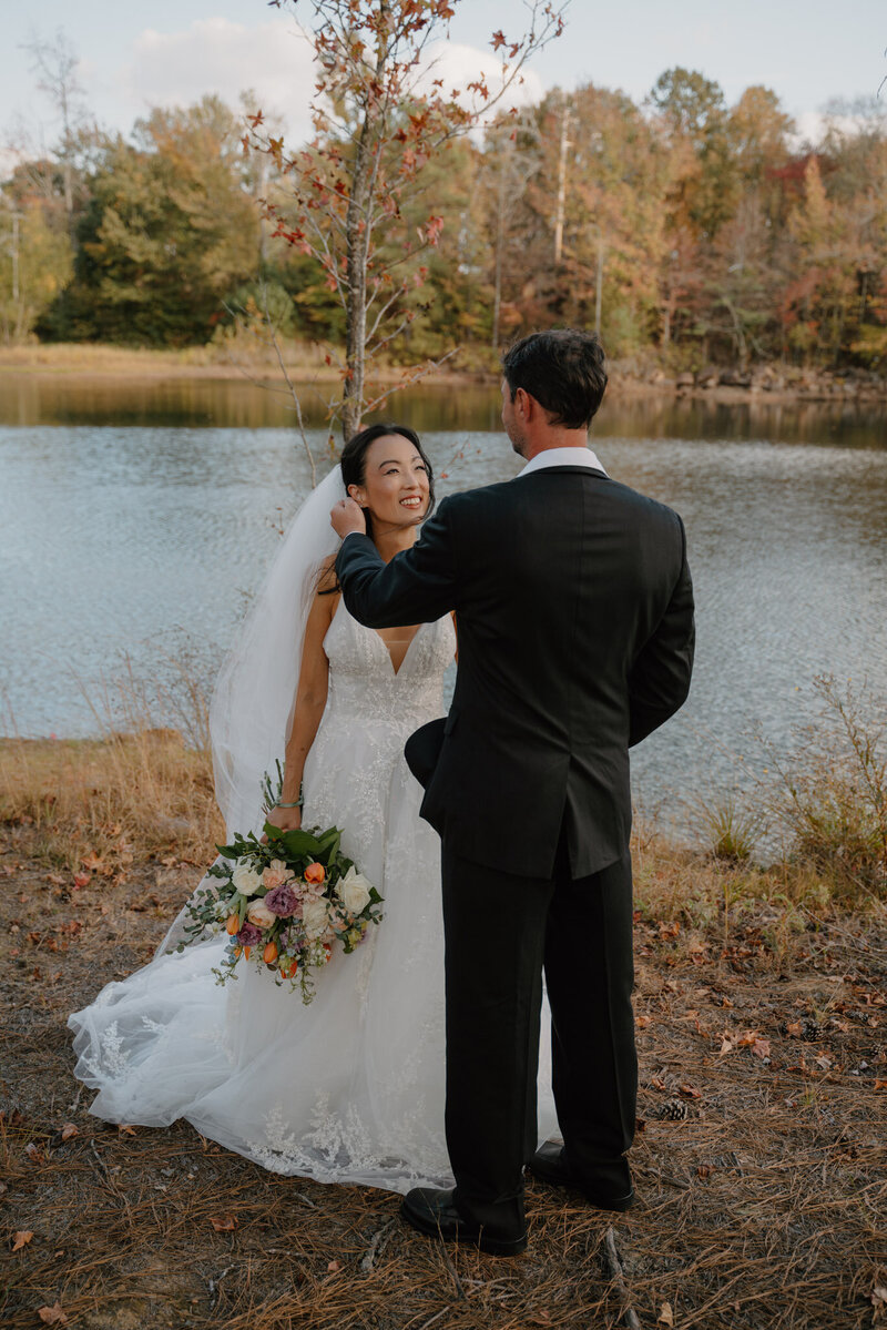 photo of groom playing with brides hair near a lake