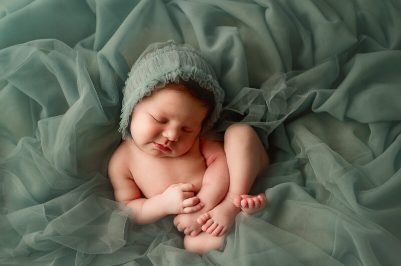 Posed Newborn laying on her back in green tulle