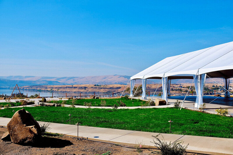 Big rock and green grass with white tent at Celilo