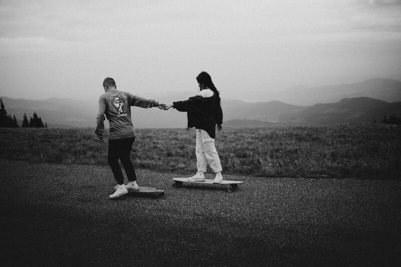 black and white image couple holding hands on skateboards