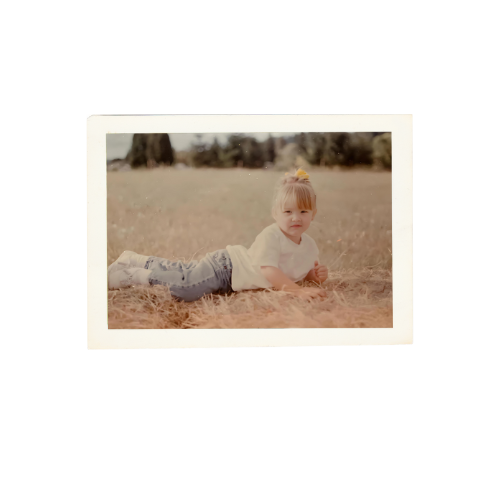 Young child lies on grass on PNW ranch.