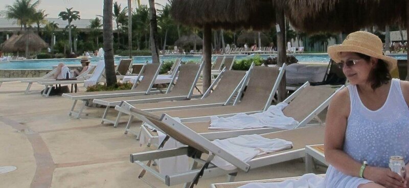 Leticia sitting on chair near pool with palm trees