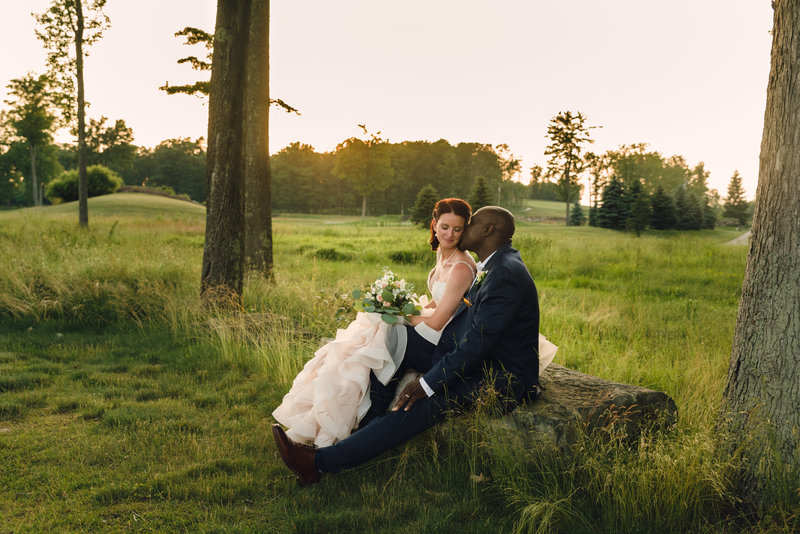 Bride and groom sitting on log at Nemacolin venue