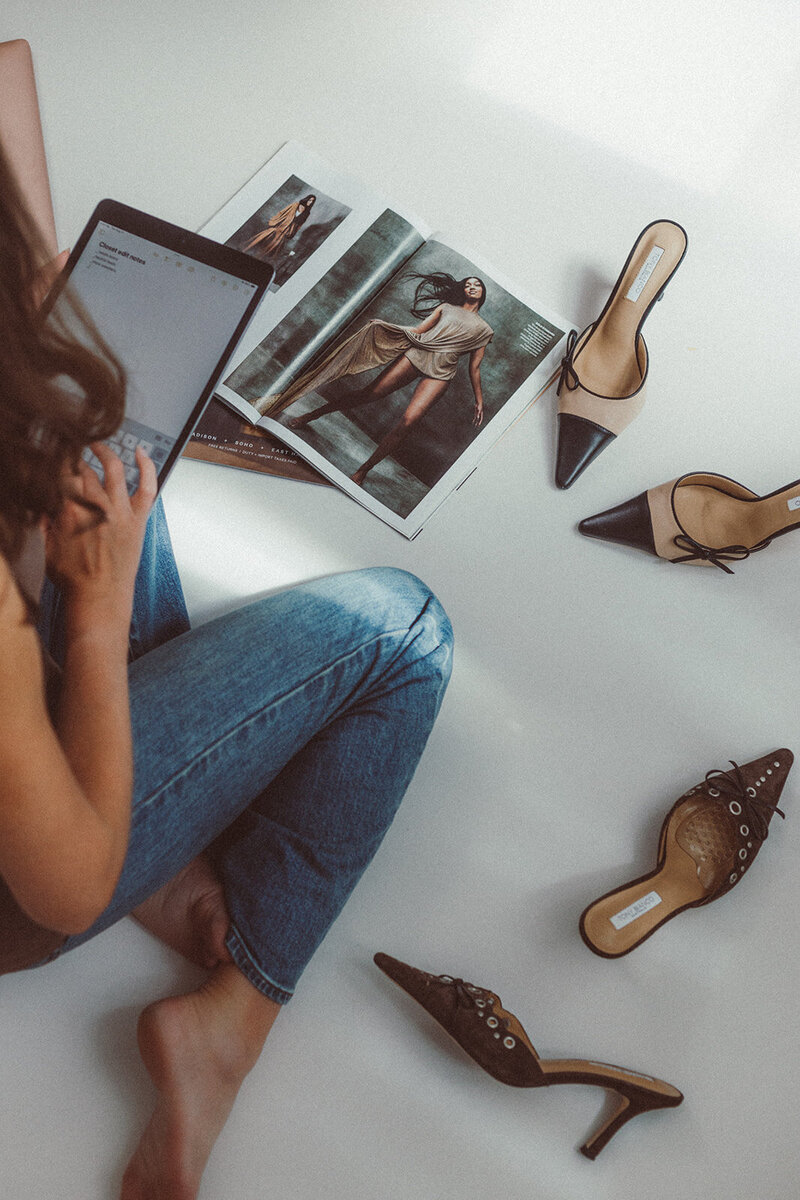 a woman wearing blue jeans surrounded by shoes and fashion magazines