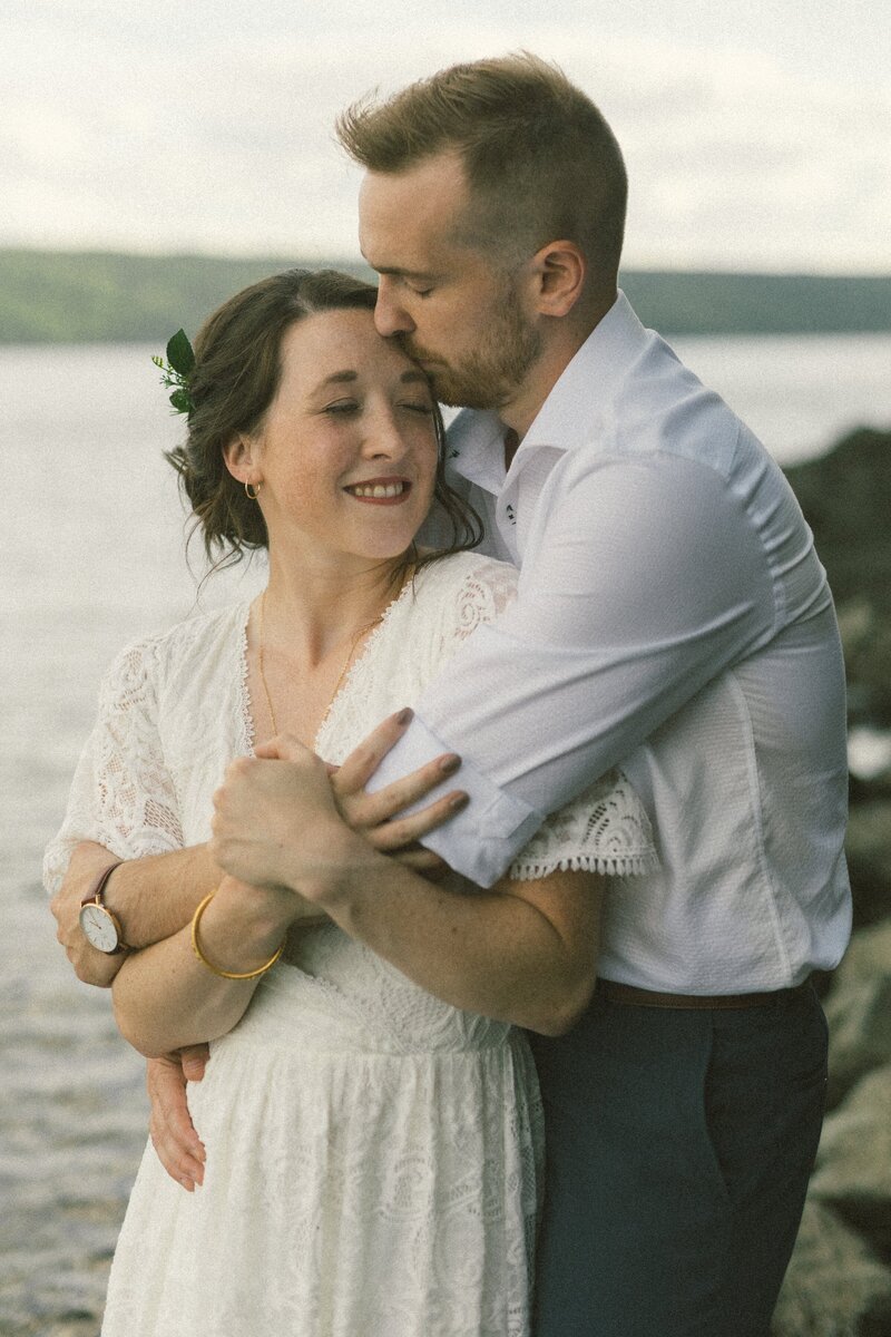 groom kisses bride's forehead while she laughs