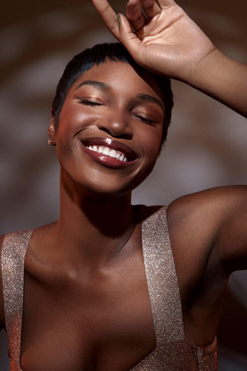 Joyful portrait of Shae with radiant skin and a wide smile, captured by Ylva Erevall in soft lighting.