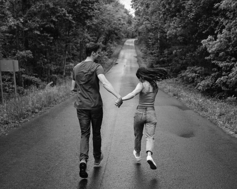 Couple frolicking down a mountain road