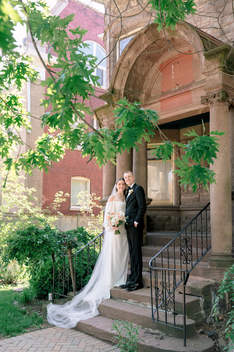 A newly married couple stand on the stone steps of an old manor in Chicago.