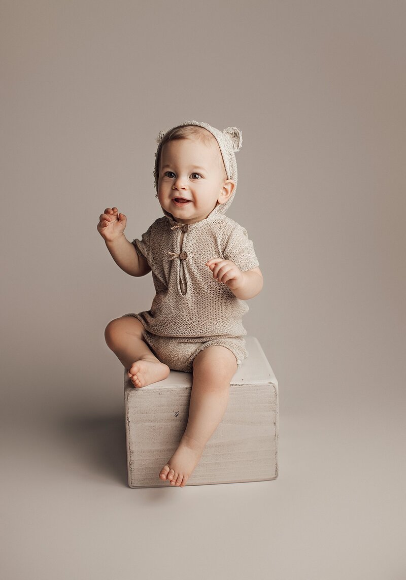 Baby smiling with open mouth and sparkling eyes during fun milestone session