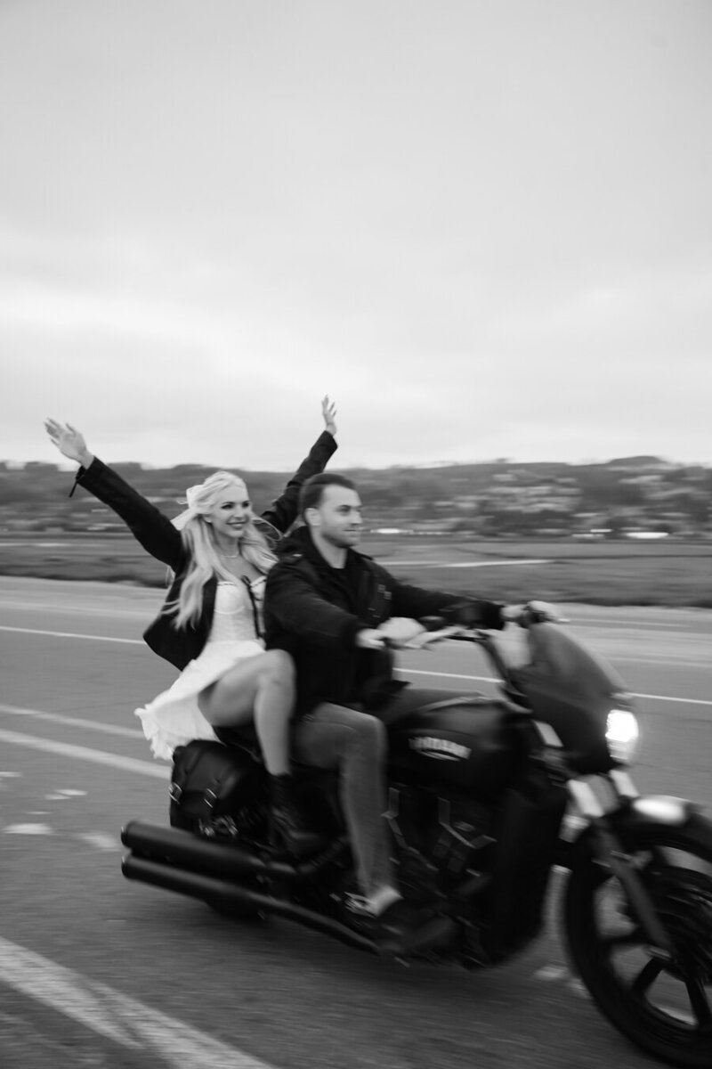 man and woman riding a motorcycle down a road