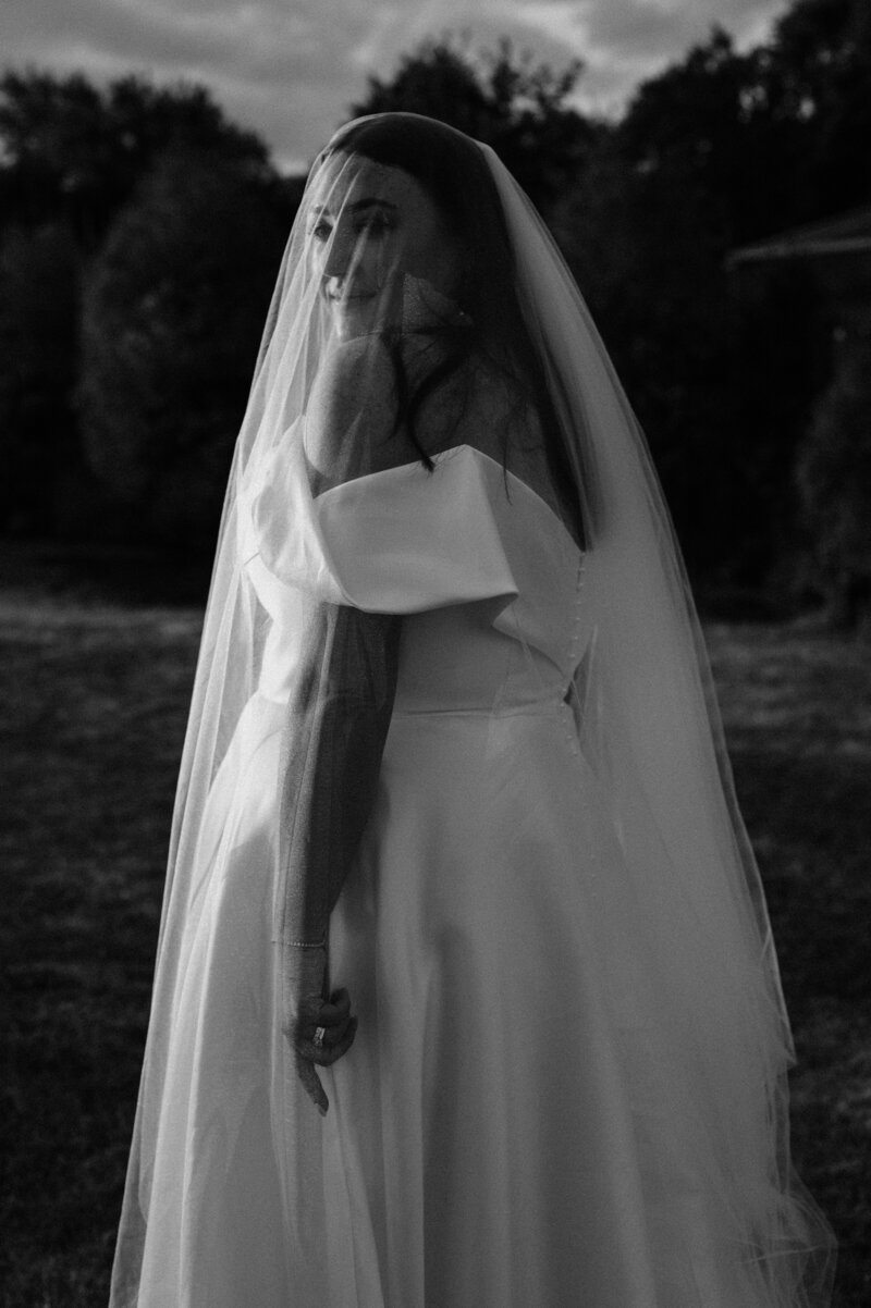 black and white shot of bride with veil over face at sunset at bangor farm