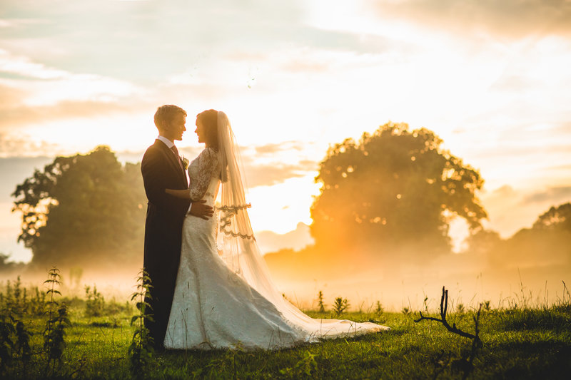 marquee wedding at a manchester home couple walking in a field at sunset