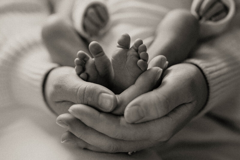 Mother cupping newborn's feet in hands