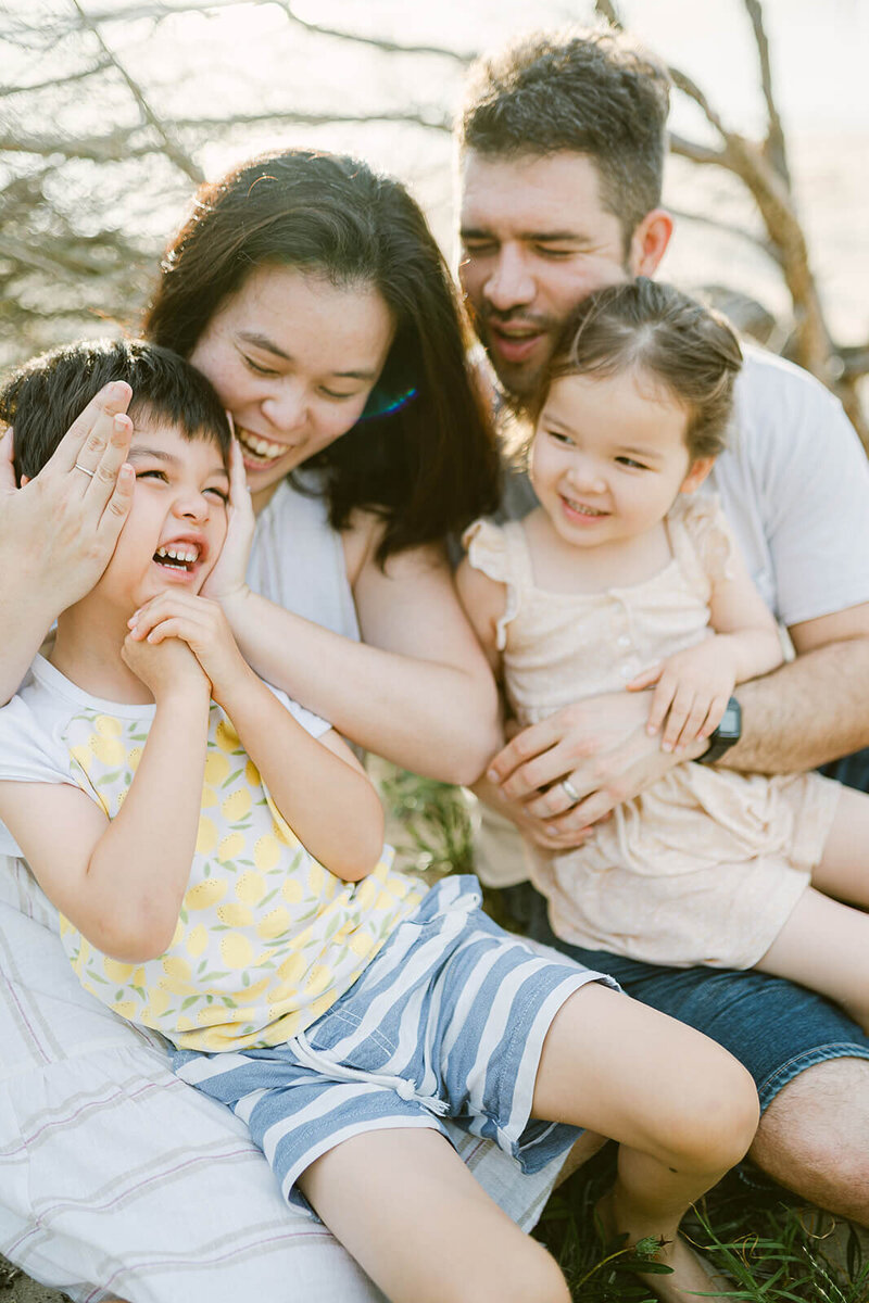 Mum, dad and kids mid-laugh, playing together on a Sydney beach during a playful sunrise photo session
