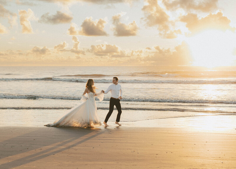 bride and groom holding hands on beach