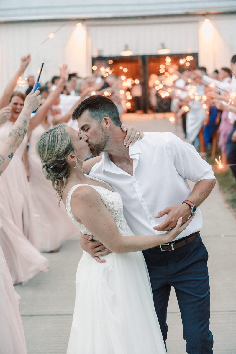 Bride and groom kiss after sparkler exit from their wedding