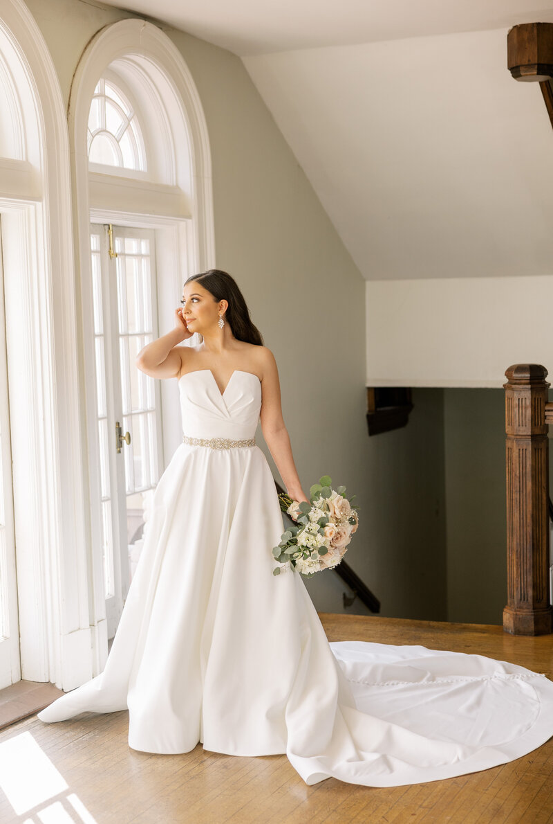 bride posing in wedding dress near a window