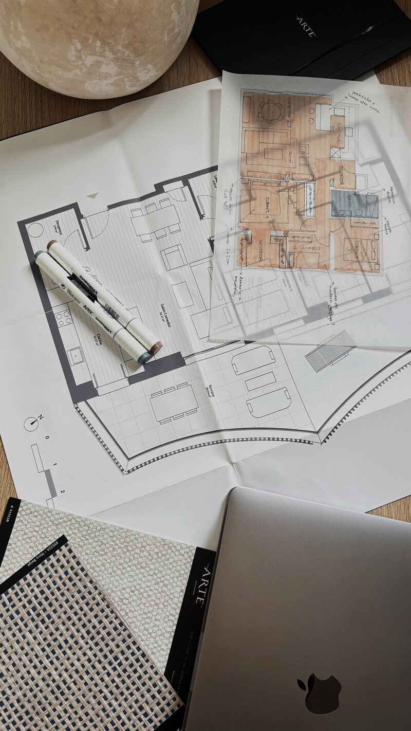 Three Pierce PR team members collaborating around a white table with laptops, notebooks, and coffee mugs, in front of large industrial-style windows.