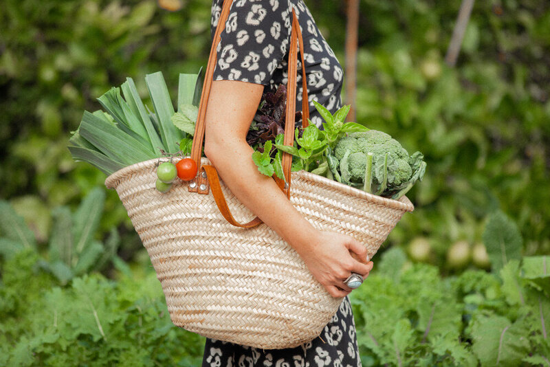 Lauren with a market bag over her shoulder, filled to the brim with fresh seasonal produce.