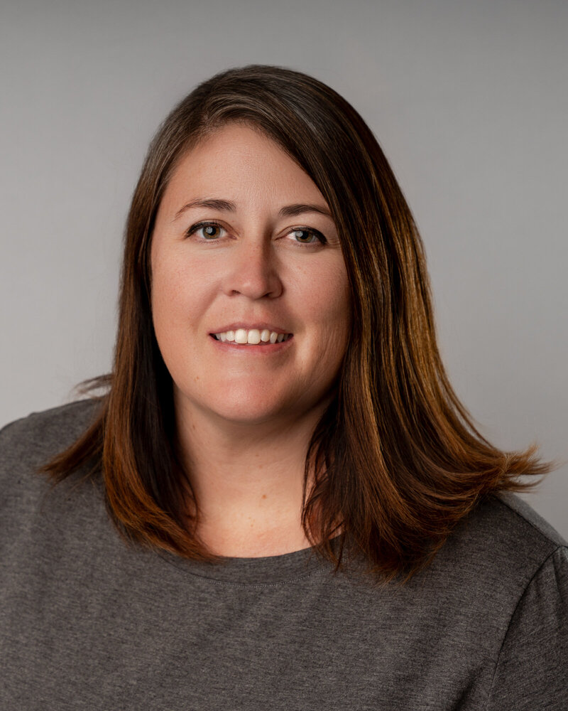 Megan Bogart, founder of Closing Photos, posing with camera in a bright yellow shirt