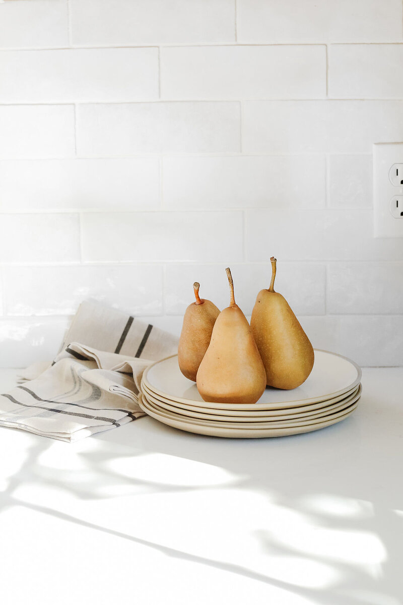 Minimalist plate of fresh pears on a white counter, capturing clean kitchen styling.