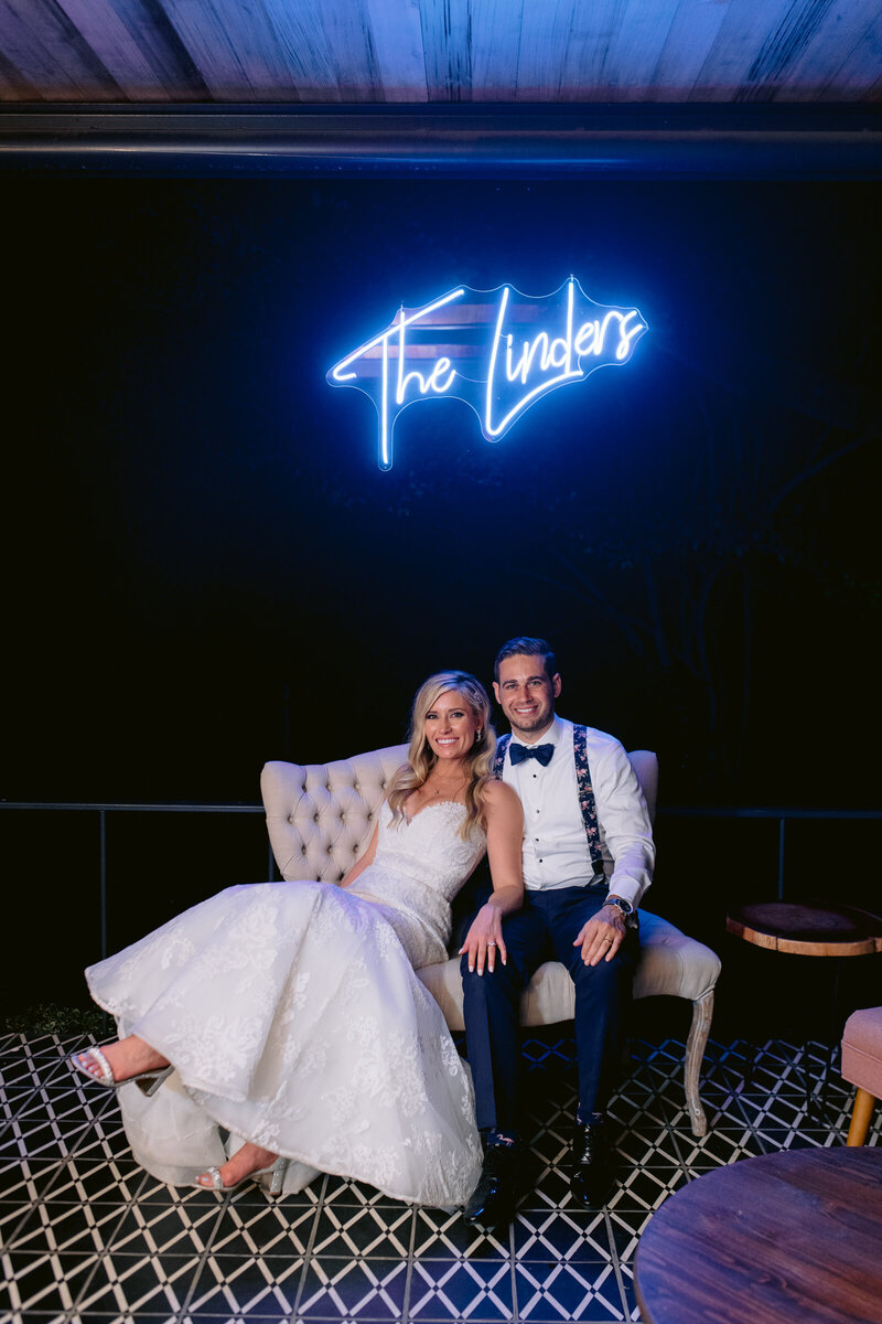 bride and groom with neon wedding sign