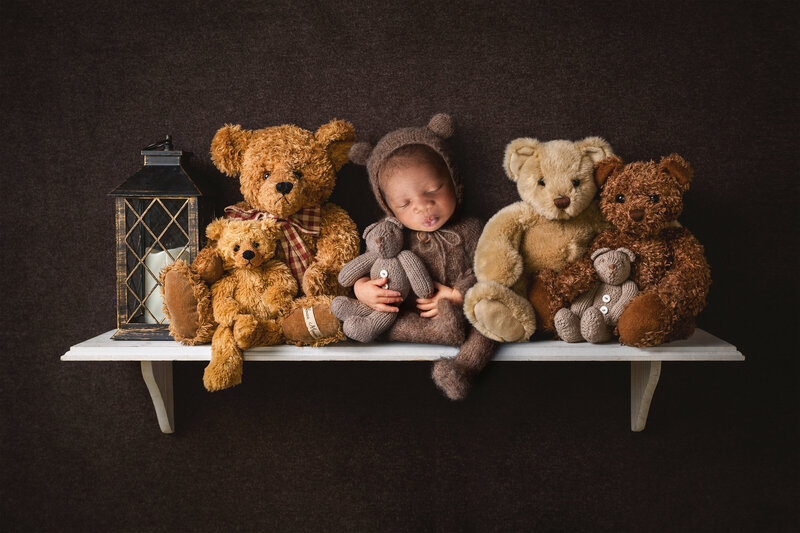 Baby boy on shelf with teddy bears