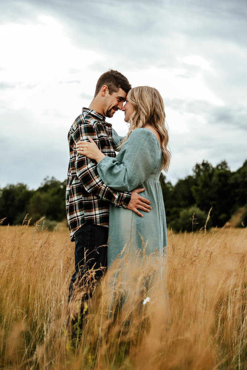 Couple embracing face to face in a field on a gloomy day.