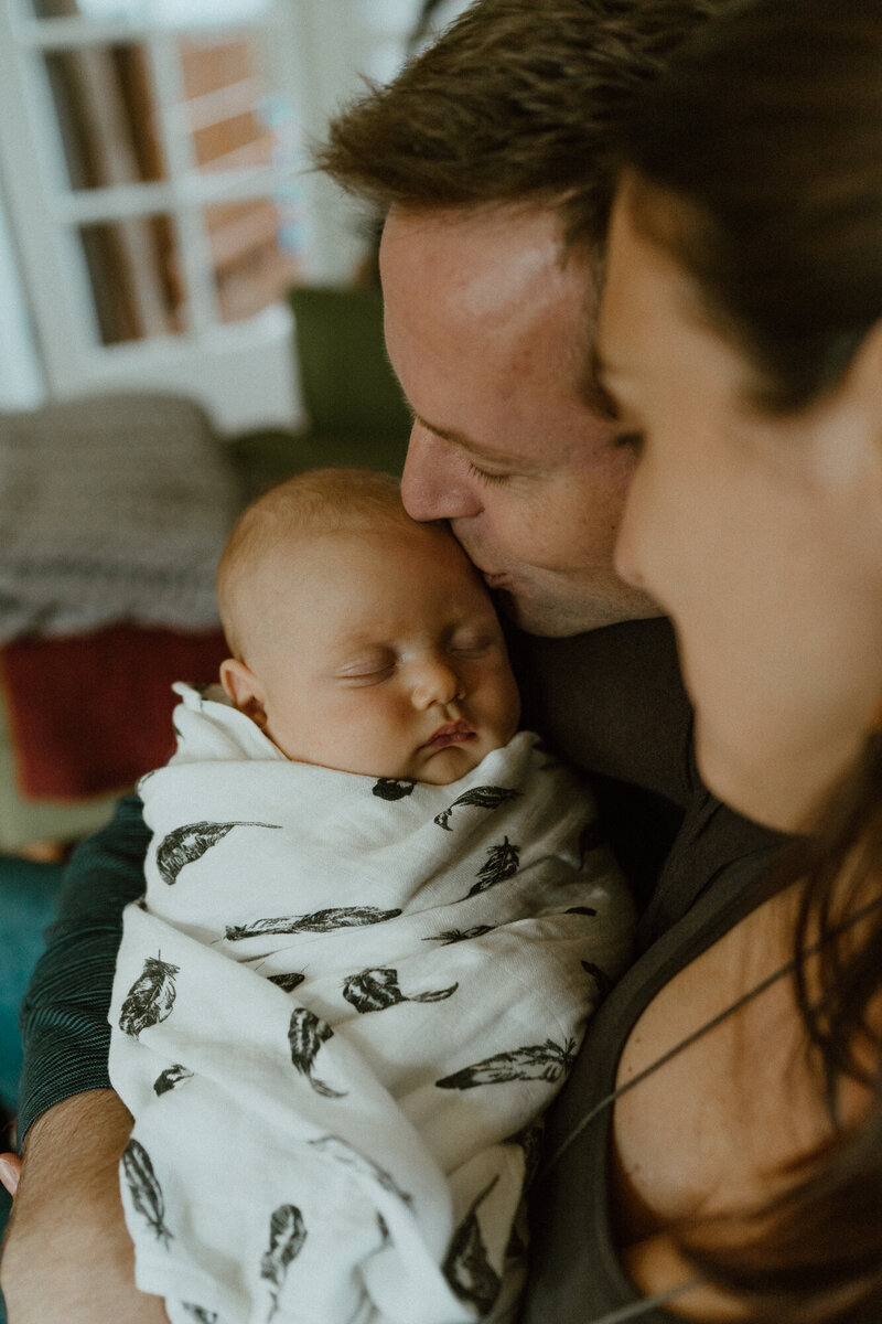 father holding and kissing newborn daughter