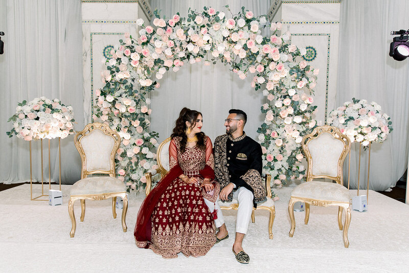 bride and groom sitting on traditional south asian stage