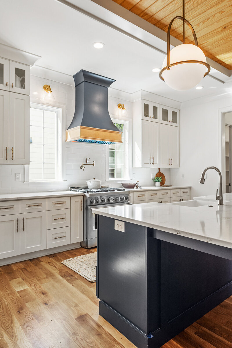 white and black kitchen with custom range hood and sconces