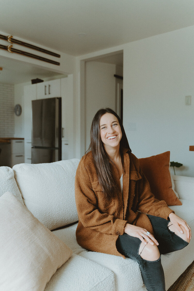Woman sitting on a couch holding her phone as if she is texting someone
