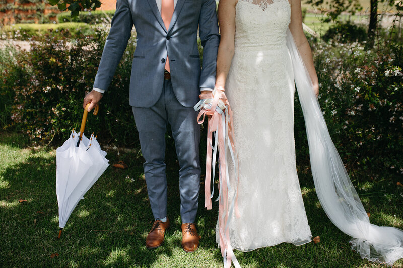 A bride and groom have their hands tied with ribbons in a wedding tradition. It is a whimsical and fun moment