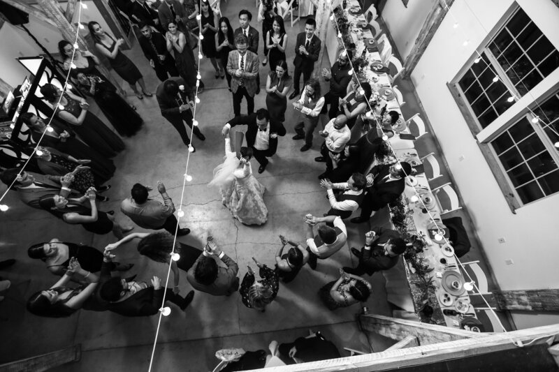 Photo of bride and groom dancing in the middle of a circle of guests taken from the second floor of the reception space at Quincy Cellars