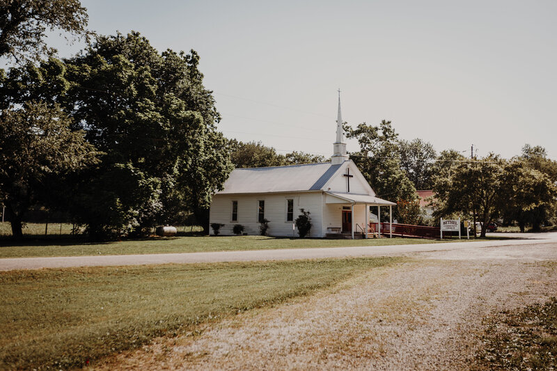 small white church next to large tree