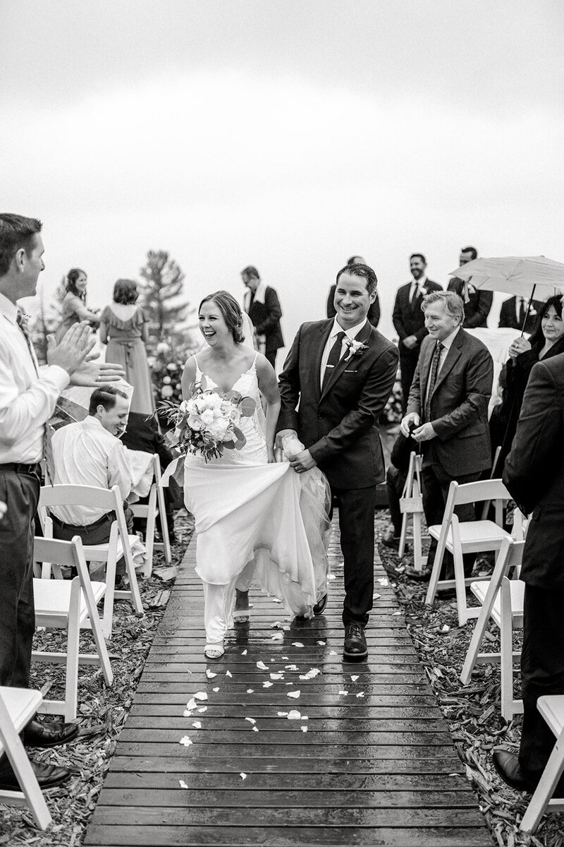 Tiffany Longeway Photography captures a joyful and triumphant moment as the newlyweds walk down the aisle amidst the rain at Thomas Fogarty Winery in Woodside, California. The scenic beauty of the winery and the couple’s happiness shine through, making it an ideal venue for couples seeking a picturesque and heartfelt wedding celebration, rain or shine.