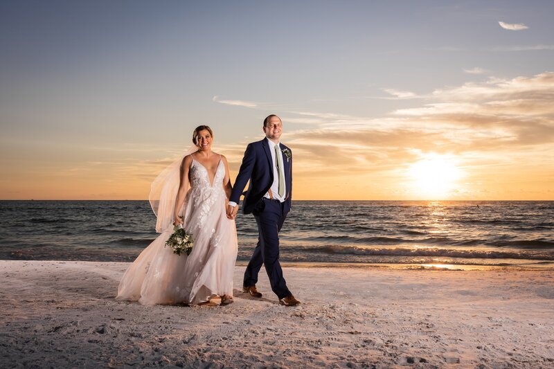 Bride and Groom walking down the beach holding hands at sunset by Love and Style Photography