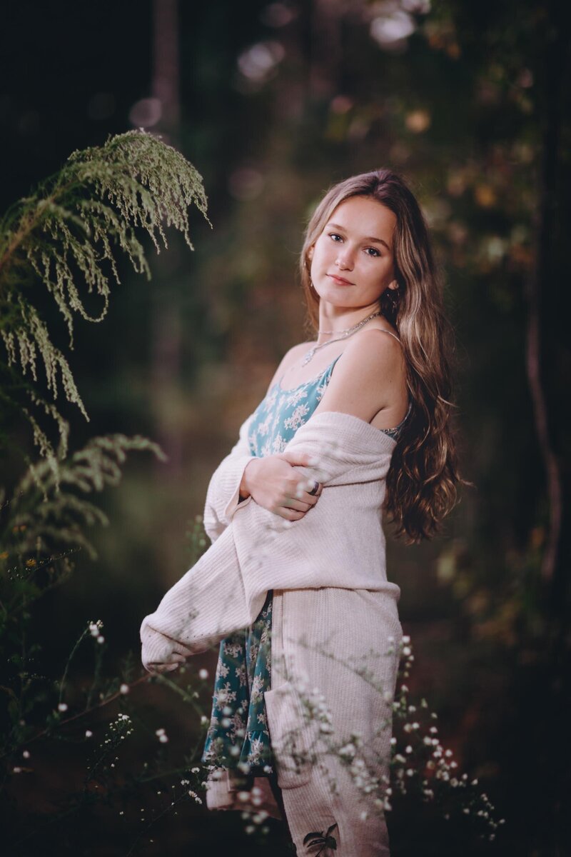 A beautiful girl with long brown hair looks over her shoulder during her senior portraits.