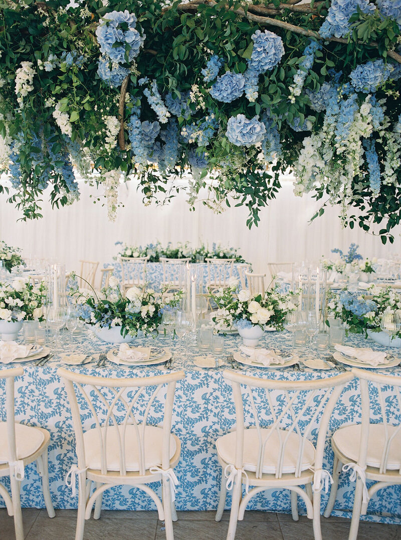 beautiful blue wedding tablescape with blue florals hanging above
