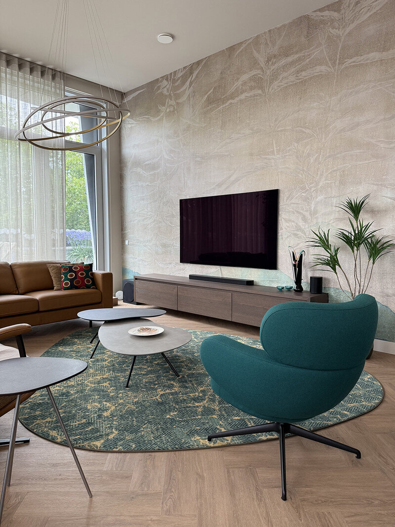Woonkamer met ronde groene fauteuil, modern vloerkleed en warme houttinten in een sfeervol interieur