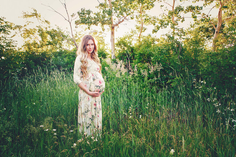 expectant mom in floral dress standing in tall grass