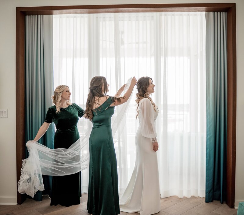 bridesmaids helping bride put on her veil