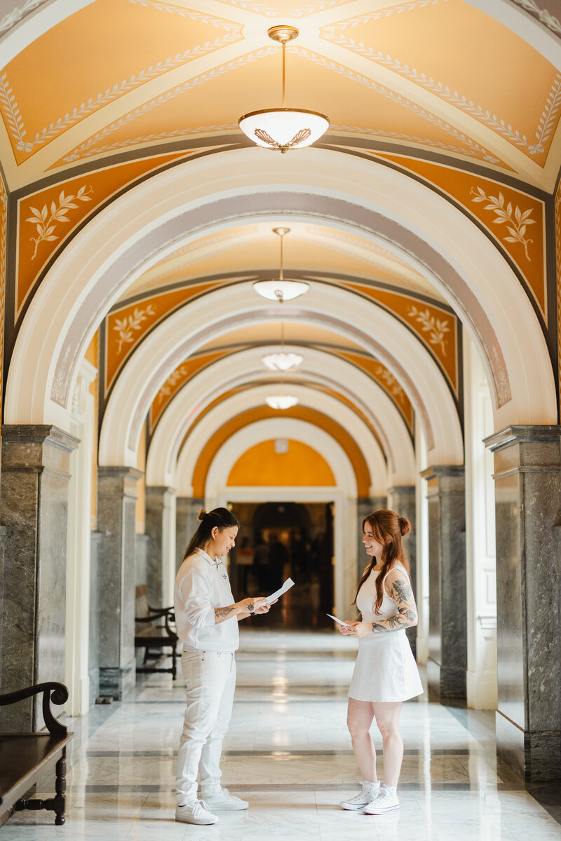 A couple reading vows to each other in a large archway during their elopement 