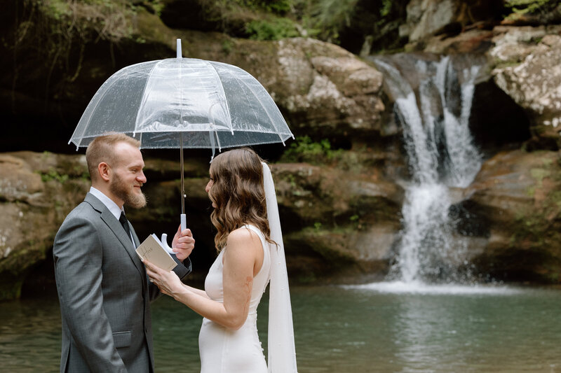 Couple saying their vows under an umbrella.